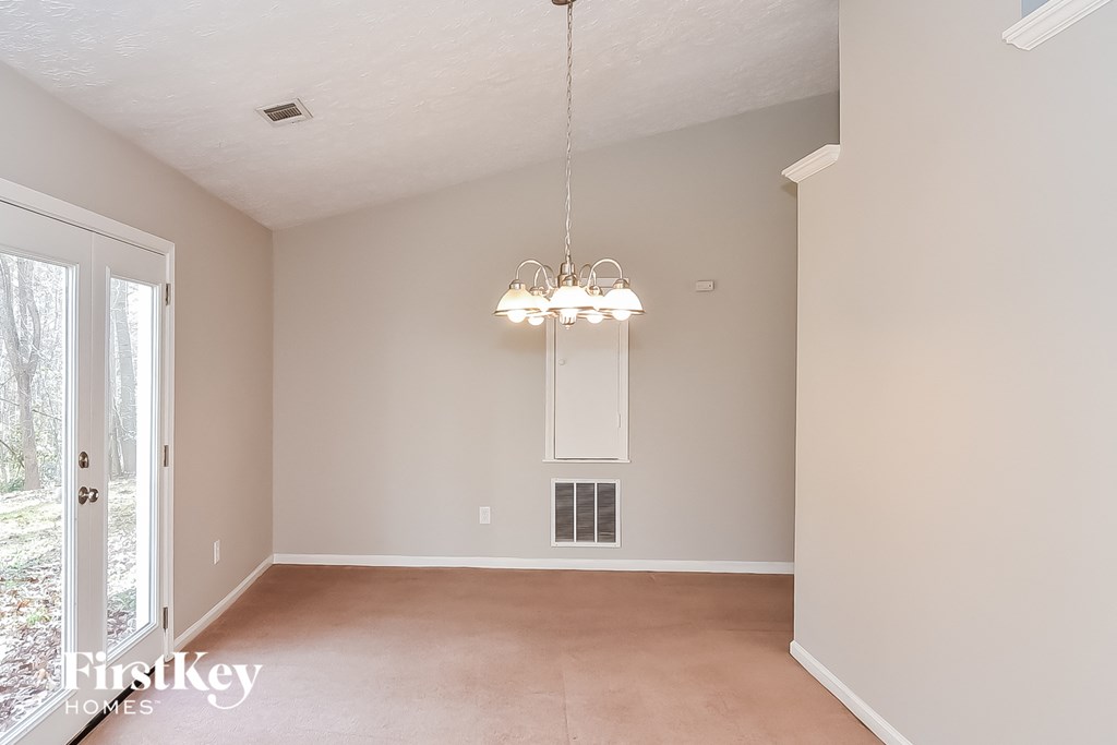 an empty living room with a chandelier and a window
