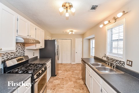 a kitchen with white cabinets and black counter tops and a stove and sink