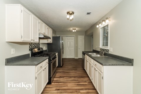 A kitchen with white cabinets and a black countertop.