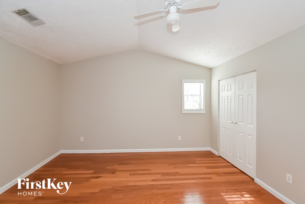 a bedroom with a wood floor and a ceiling fan