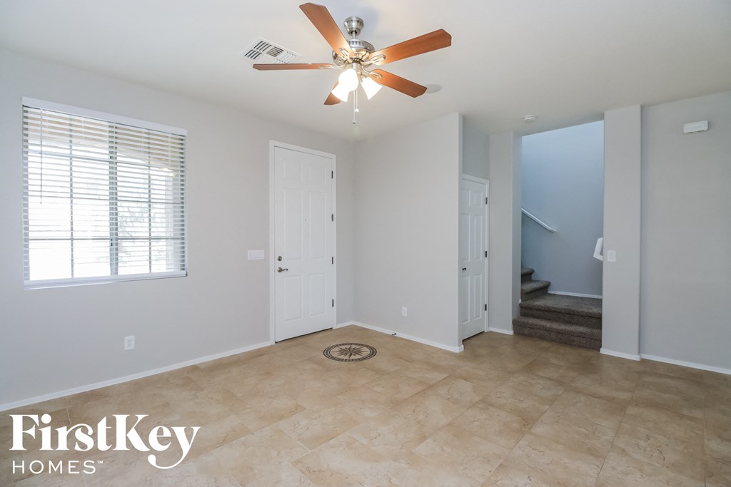 an empty living room with a ceiling fan and a staircase