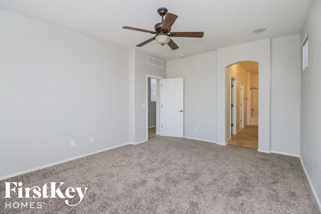 a living room with a ceiling fan and a carpet