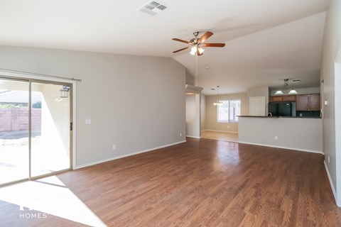 an empty living room with wood flooring and a ceiling fan