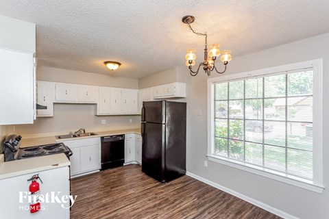 A kitchen with a black fridge and a chandelier.