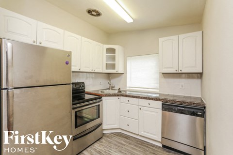 A kitchen with a stainless steel refrigerator and white cabinets.