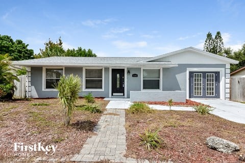 A house with a grey exterior and a black door is for sale.