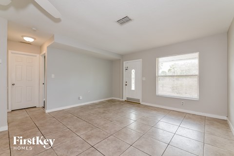 A spacious empty room with tile flooring and two doors.