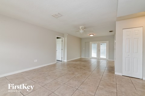 A spacious room with tile flooring and a ceiling fan.