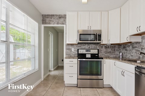 A kitchen with a stove, oven, microwave and cabinets.