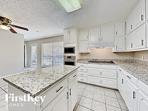 a white kitchen with granite counter tops and white cabinets