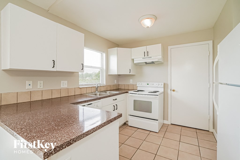 a kitchen with white appliances and white cabinets and granite counter tops