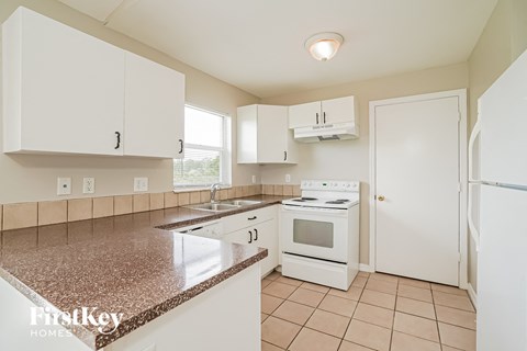a kitchen with white appliances and white cabinets and granite counter tops