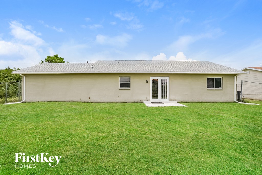 a small white house with a grassy backyard