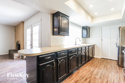 A kitchen with black cabinets and a wooden floor.