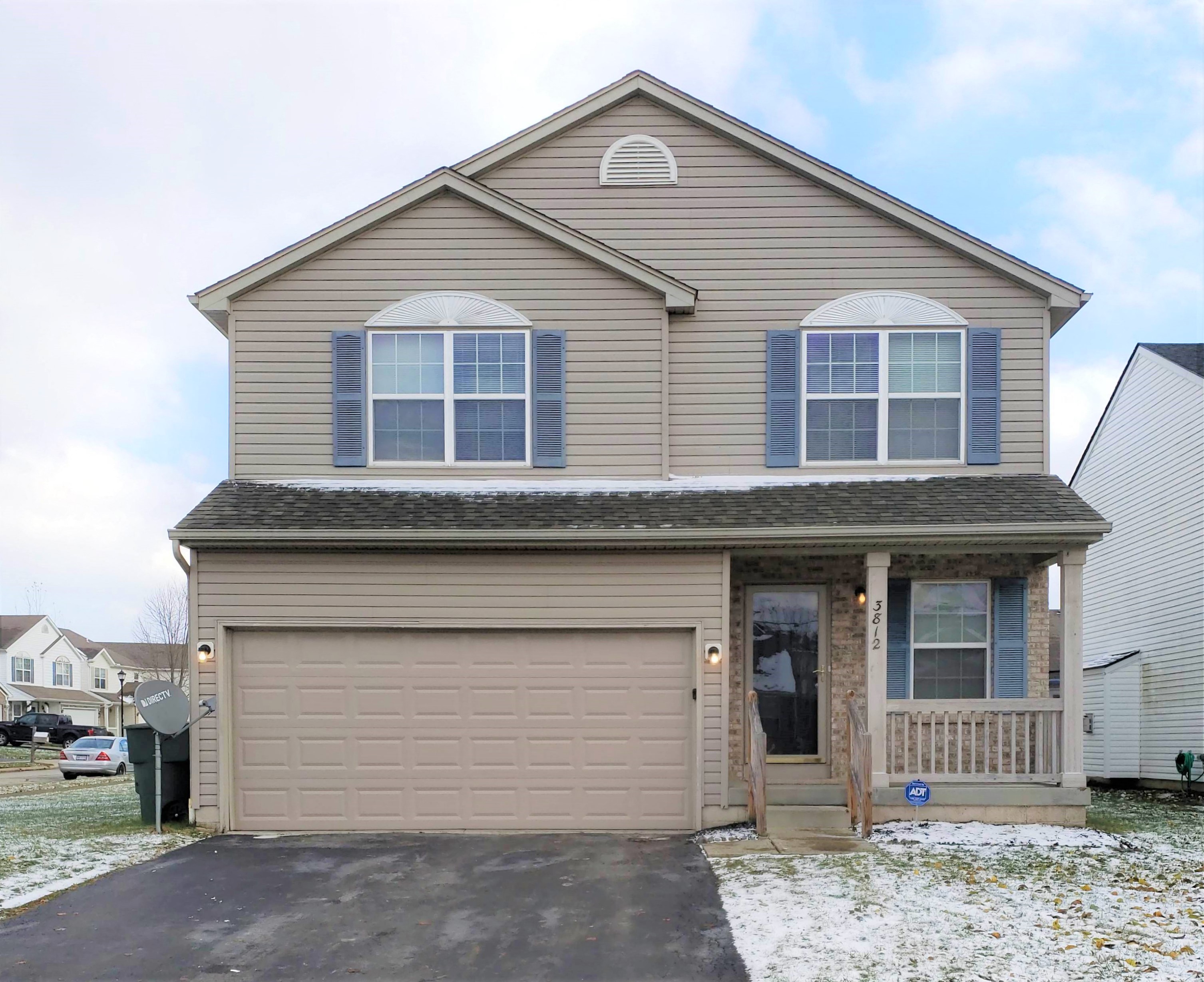 the front of a house with a garage and snow on the ground