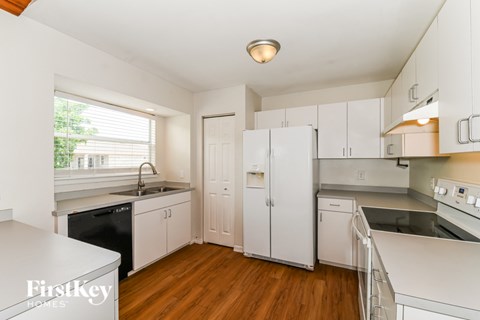 A kitchen with white cabinets and a wooden floor.