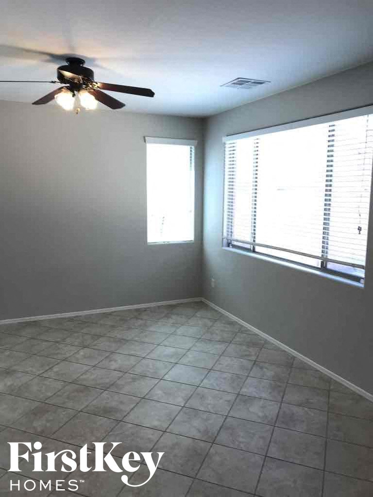 A room with a ceiling fan and a window with blinds.