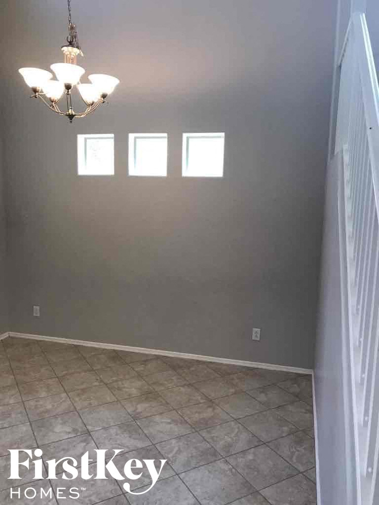 A room with a chandelier and a wall with three windows.