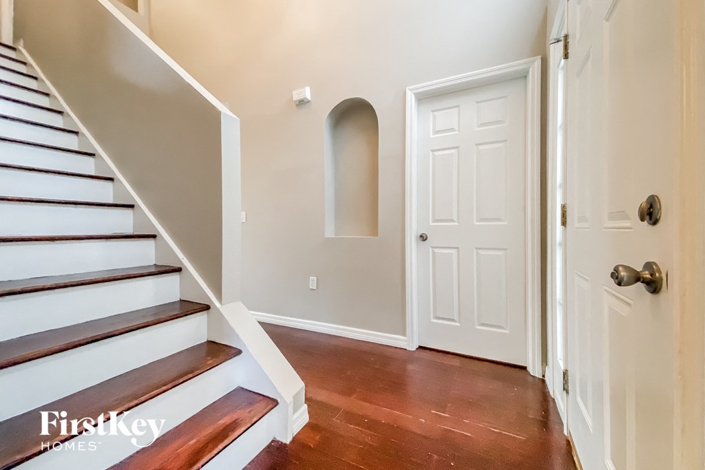 a foyer with stairs and a white door and a door to a closet