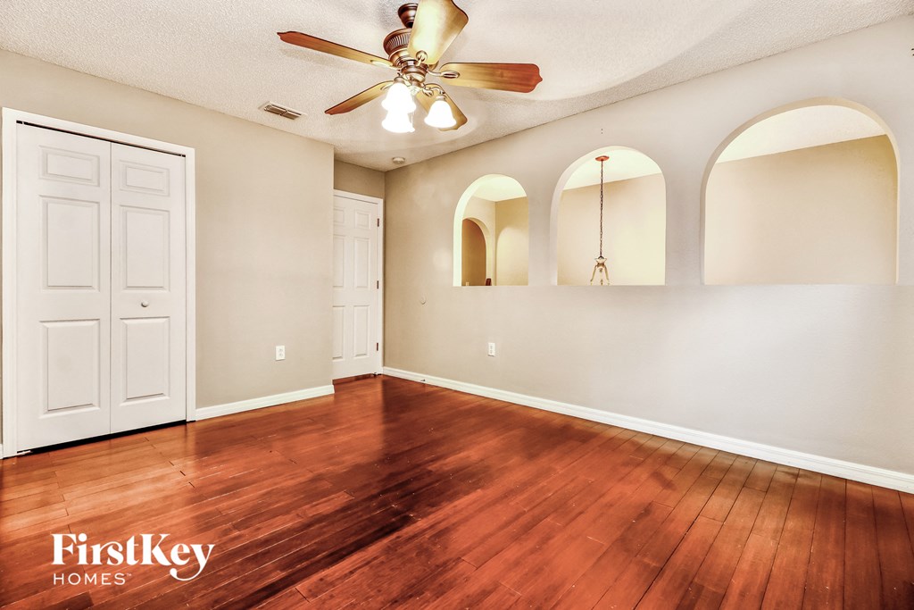 an empty living room with wood floors and a ceiling fan