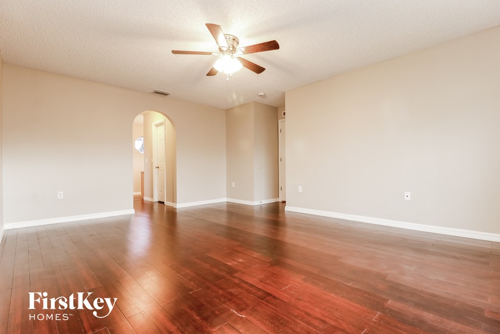 the living room and dining room with hardwood floors and a ceiling fan