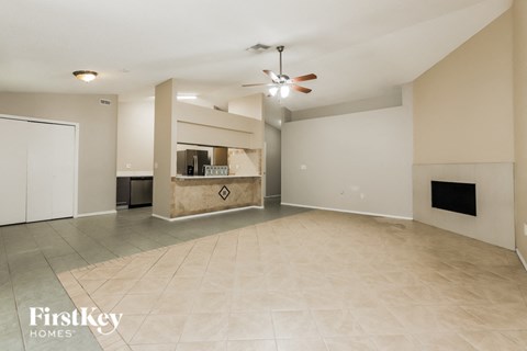 A spacious living room with a fireplace and a ceiling fan.