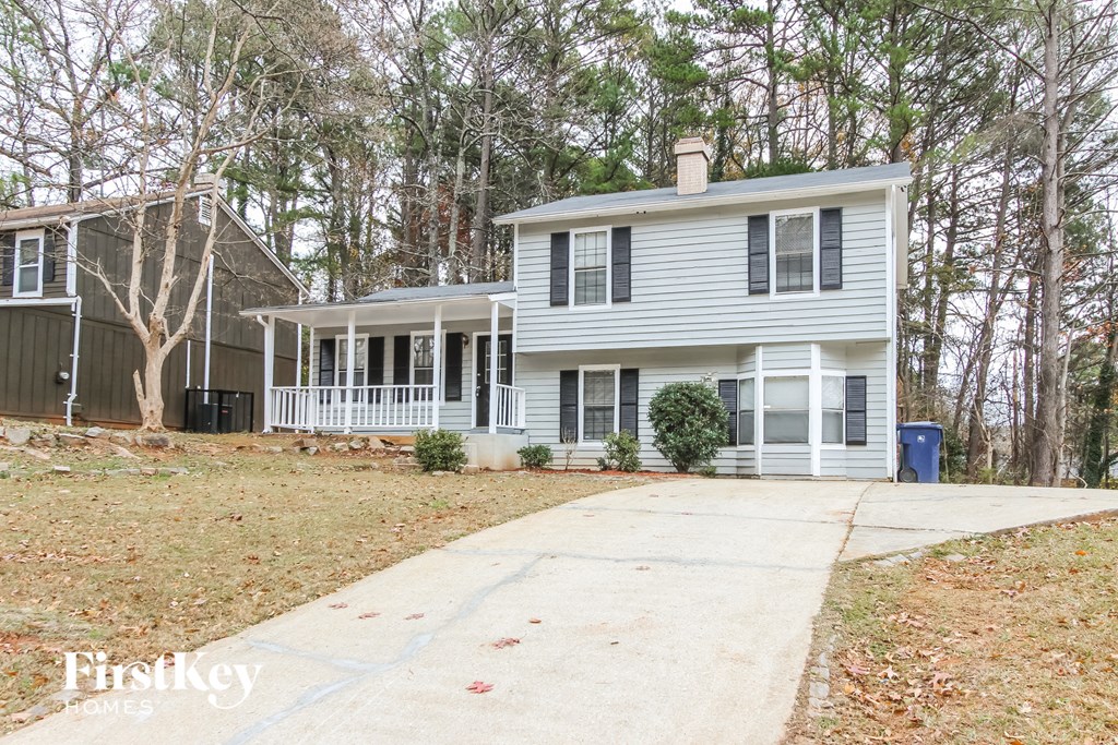 a white house with black shutters and a sidewalk