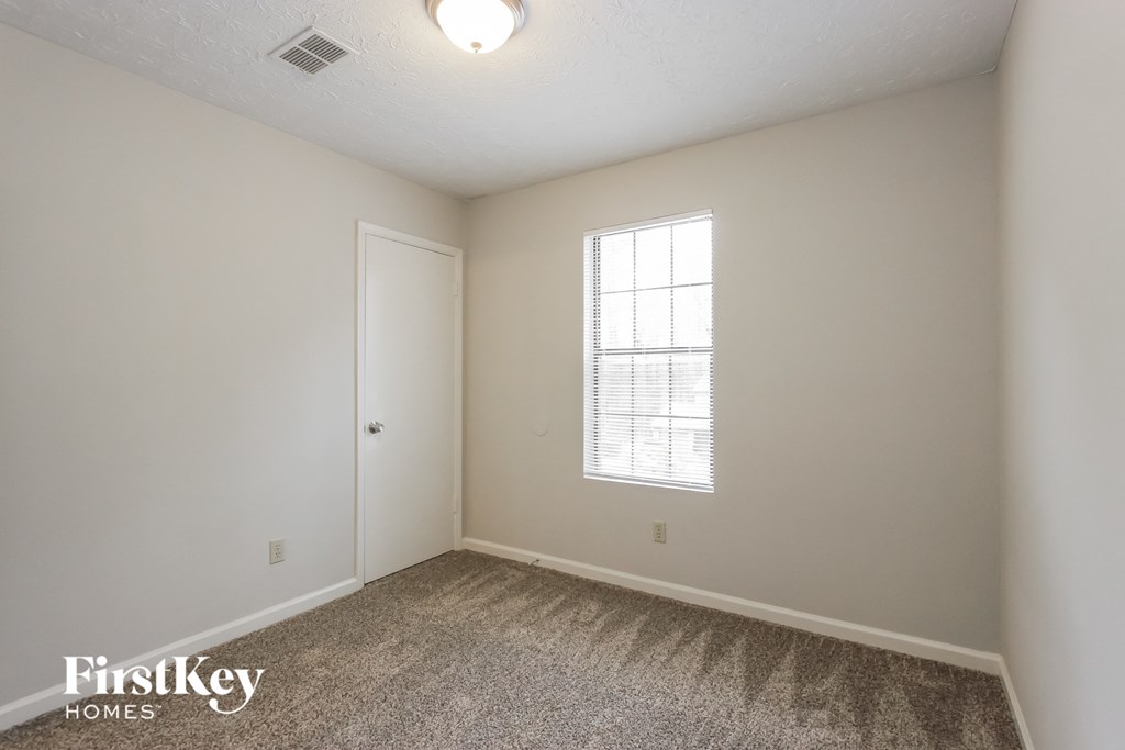 a bedroom with white walls and carpet and a window