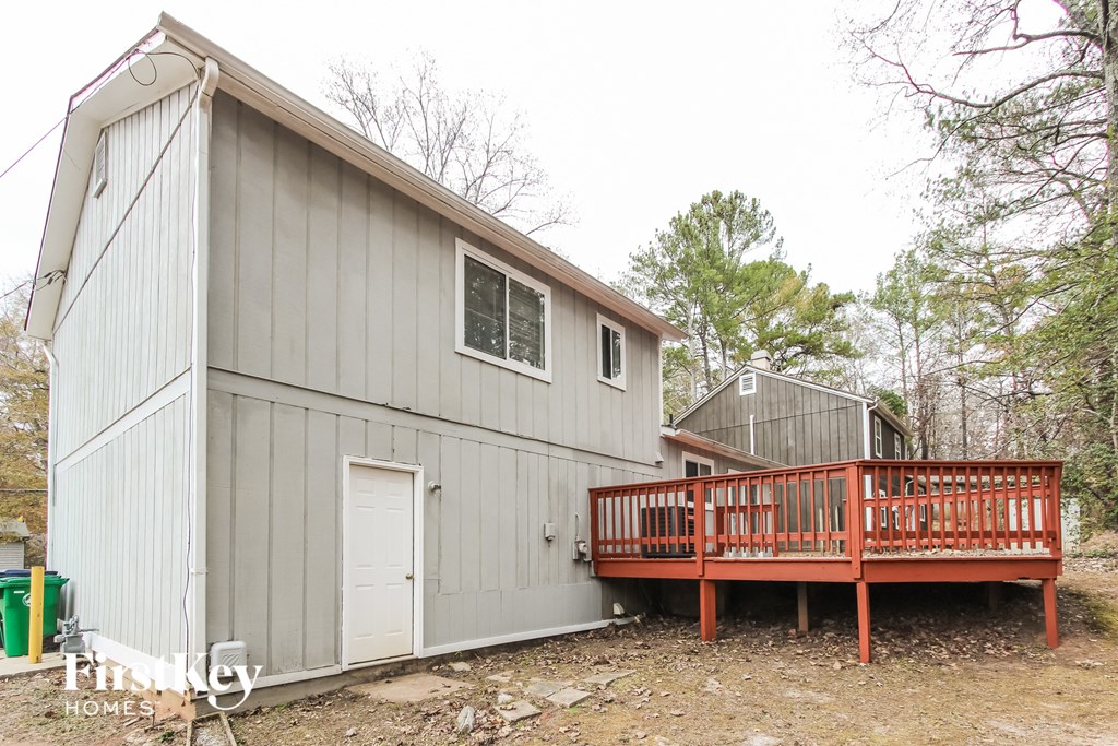 the exterior of a gray house with a deck and a white door