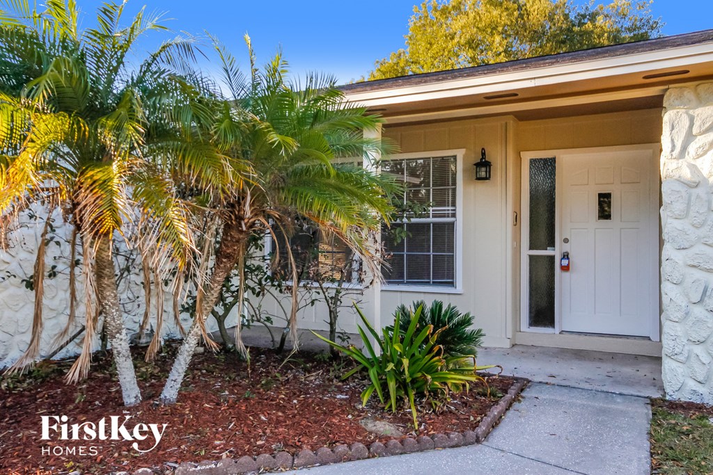 a small house with a white door and palm trees