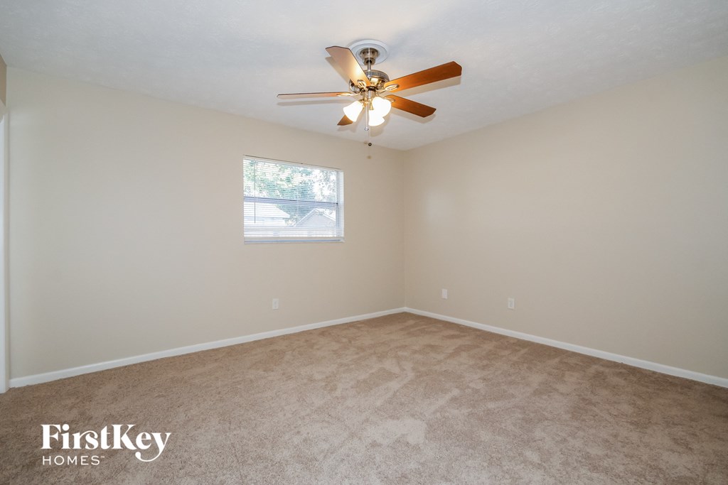 a bedroom with beige carpet and a ceiling fan