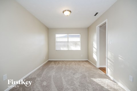 a spacious living room with carpet and a window