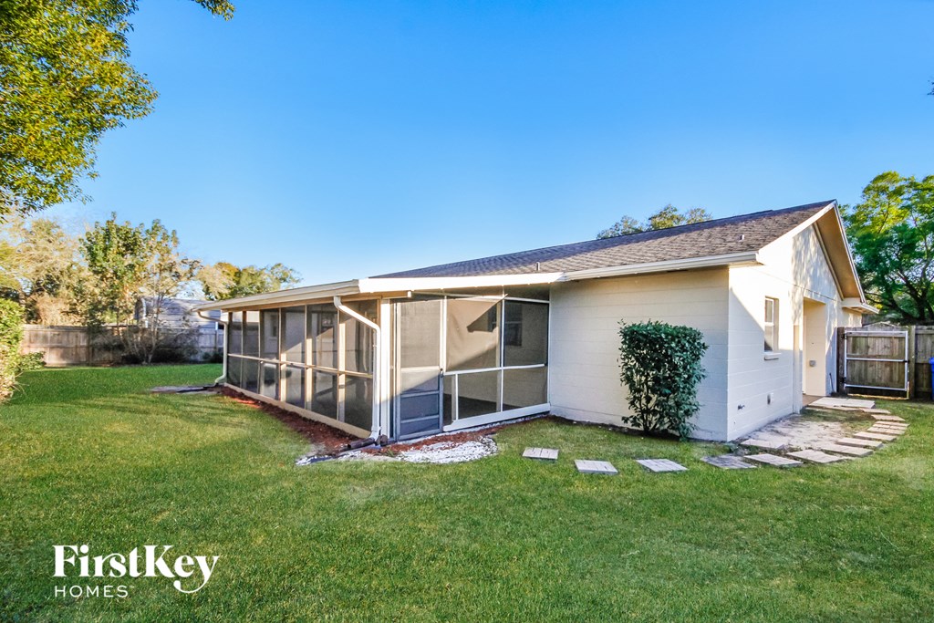 a small white house with a screened in porch and a lawn