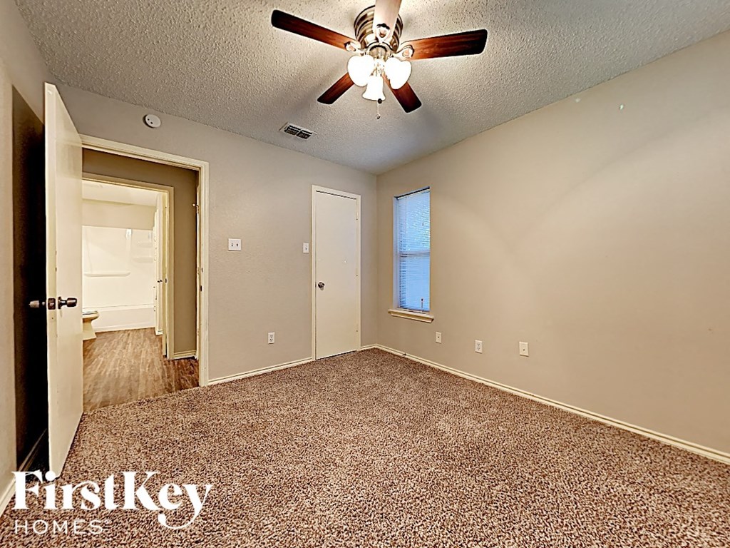 an empty room with a ceiling fan and a door to a bathroom