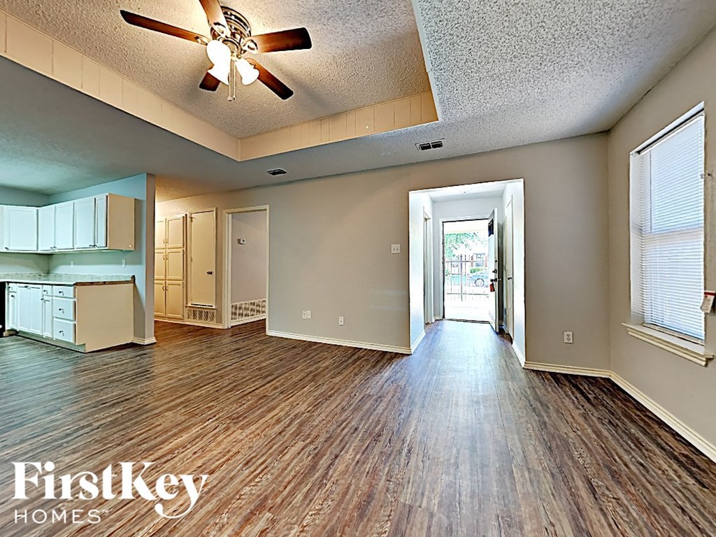 an empty living room with wood floors and a ceiling fan
