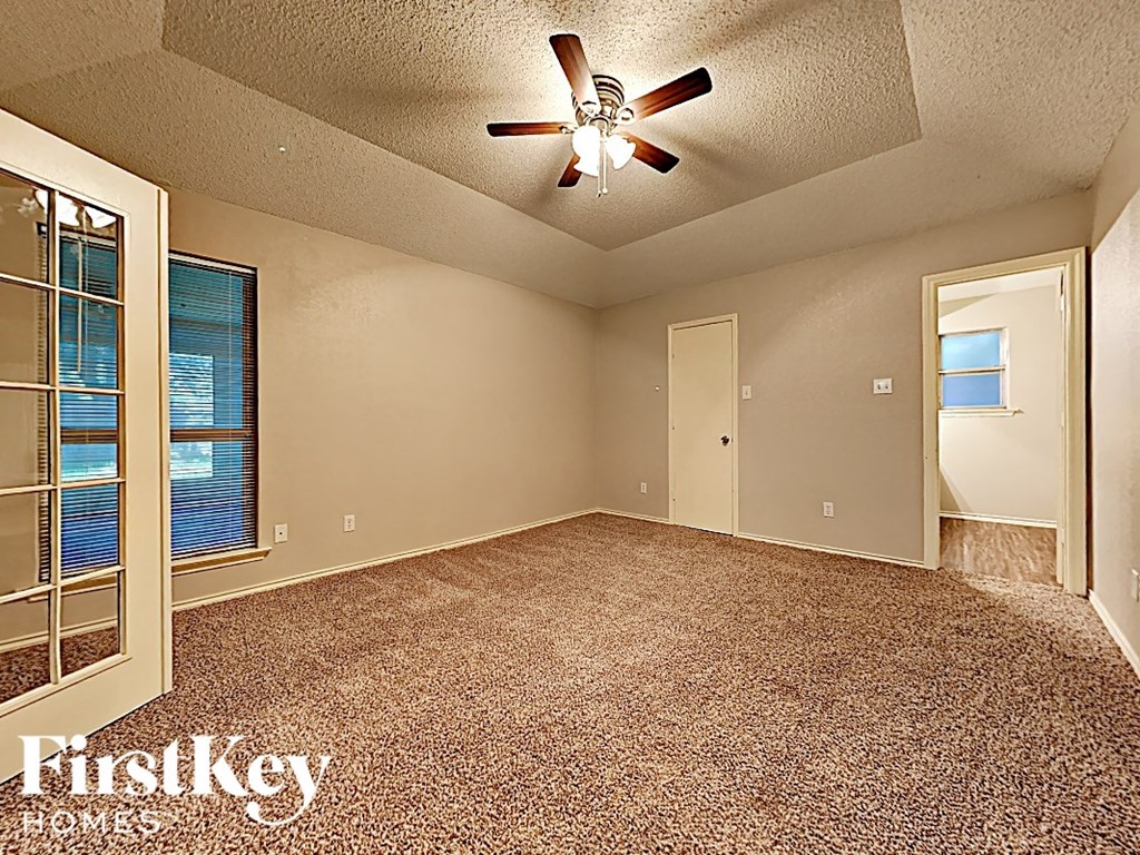 an empty living room with a ceiling fan and a window