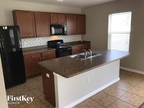 A kitchen with brown cabinets and a black refrigerator.