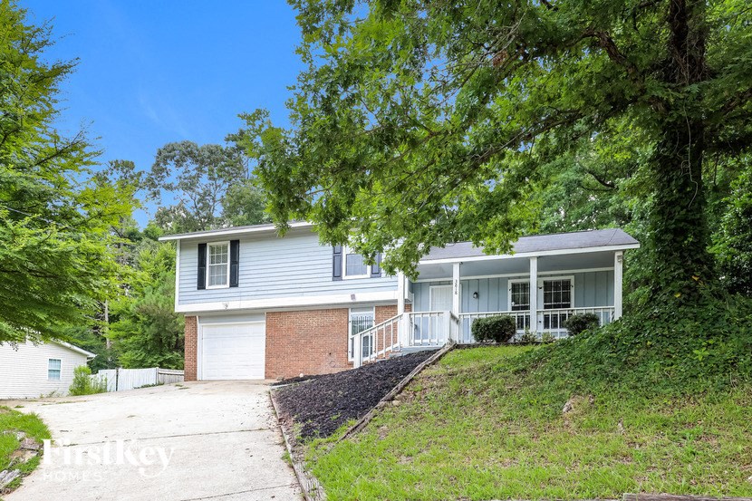 a white and brick house on a hill with trees