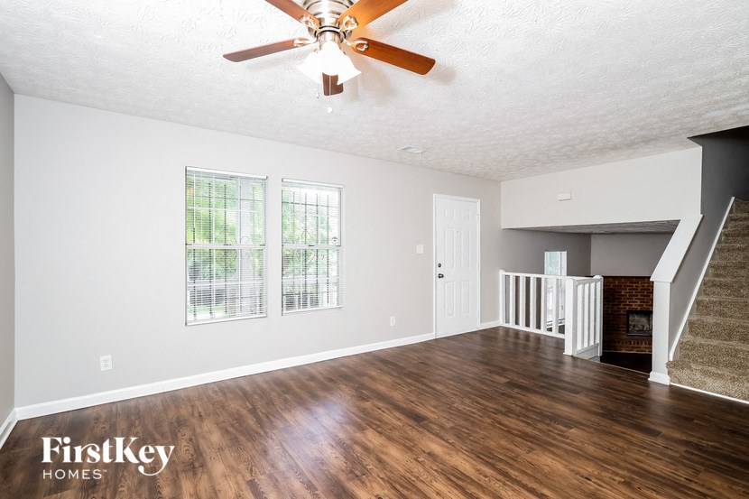 an empty living room with a ceiling fan and a staircase