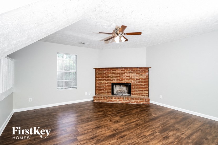 a living room with a brick fireplace and a ceiling fan