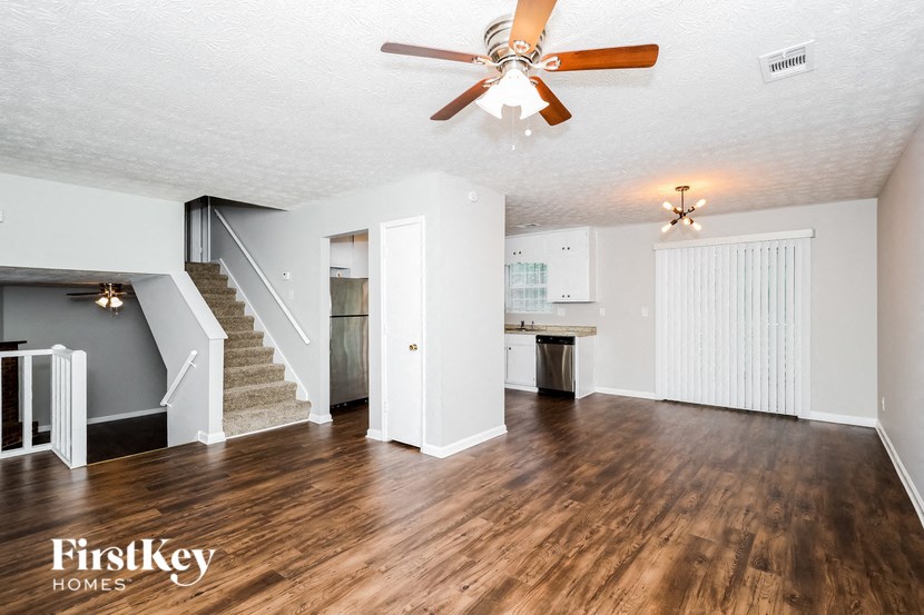 an empty living room with a ceiling fan and a staircase