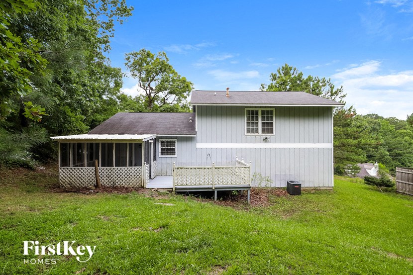 the back of a white house with a porch and a fence