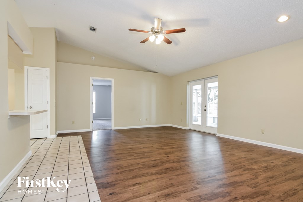 A spacious room with wooden floors and a ceiling fan.
