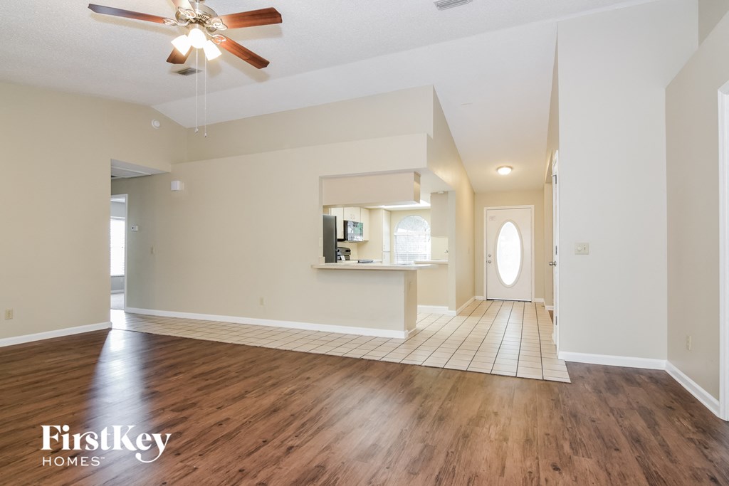 A spacious room with a ceiling fan and wooden flooring.