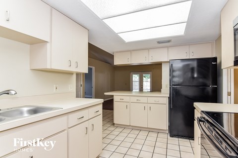 A kitchen with white cabinets and a black refrigerator.