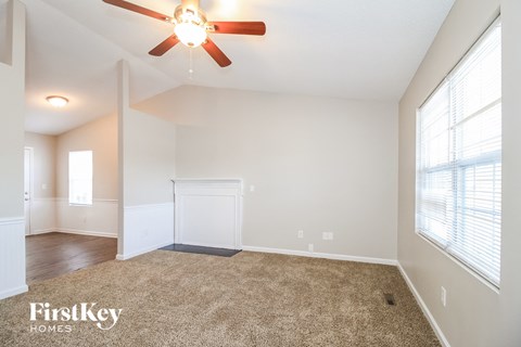 A carpeted room with a ceiling fan and a window.