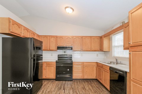 A kitchen with wooden cabinets and a black fridge.