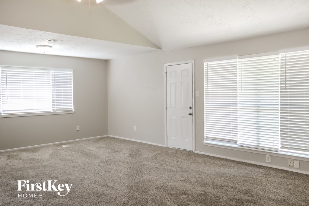 a bedroom with a carpeted floor and a white door and window