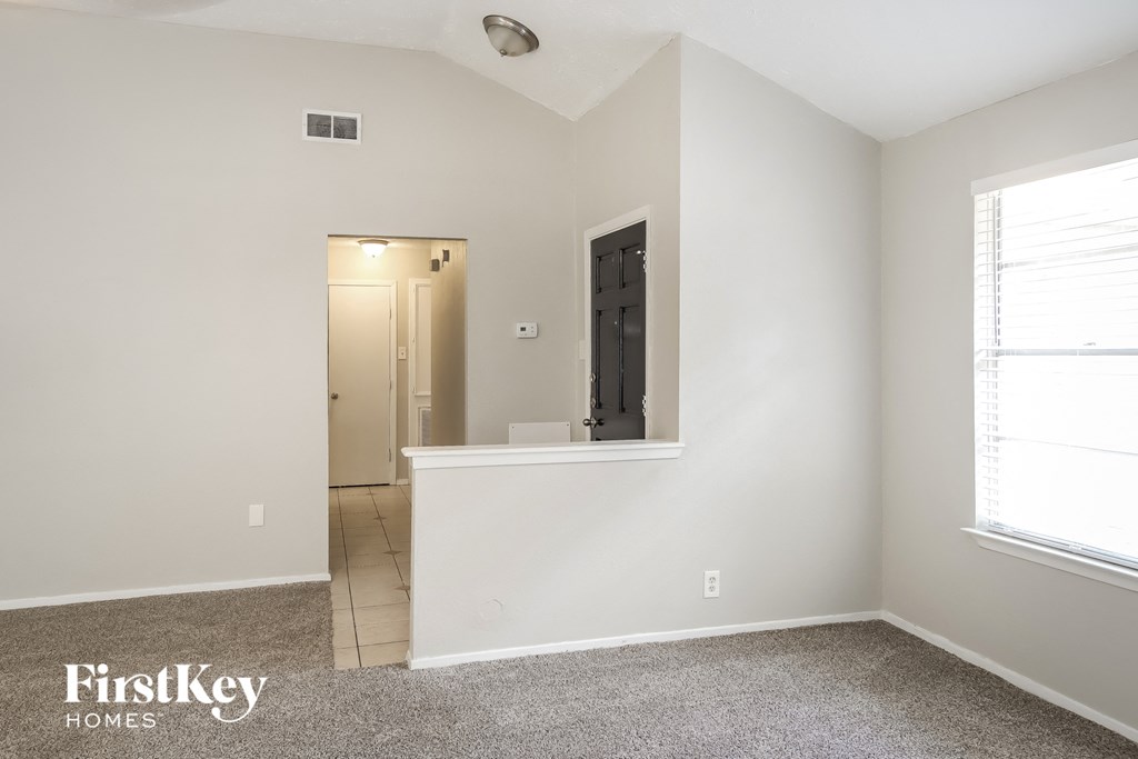 the living room of an empty home with white walls and carpet