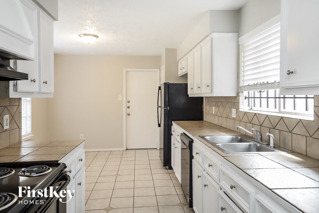 a kitchen with white cabinets and a black refrigerator